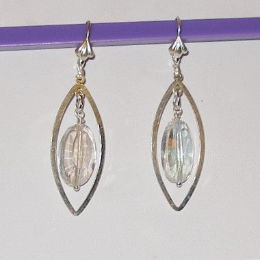Pair of silver earrings with clear crystals on a purple stick against a white background