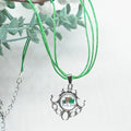 Necklace with a pendant featuring a shamrock design and text, against a light background with green leaves.