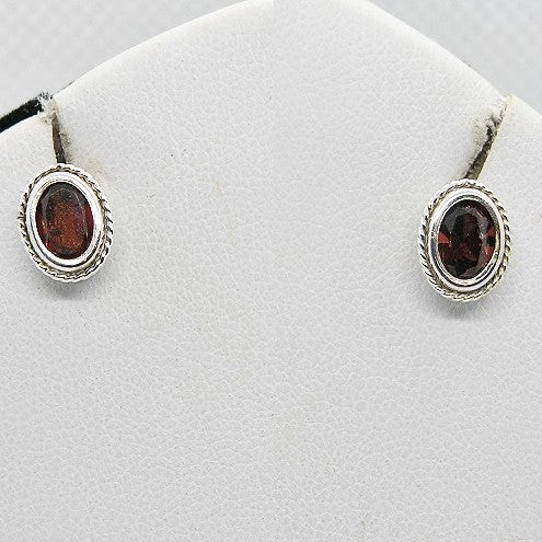 Pair of silver earrings with red gemstones on a white background