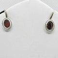 Pair of silver earrings with red gemstones on a white background