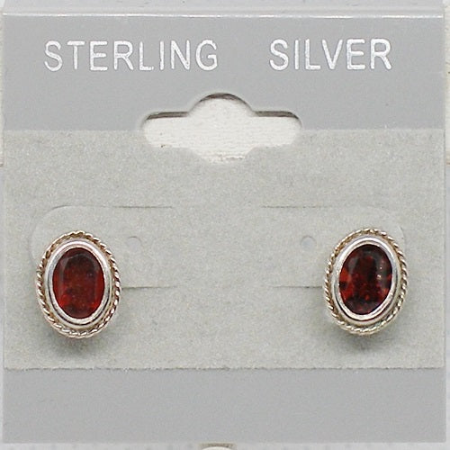 Pair of sterling silver earrings with red gemstones on a gray card.