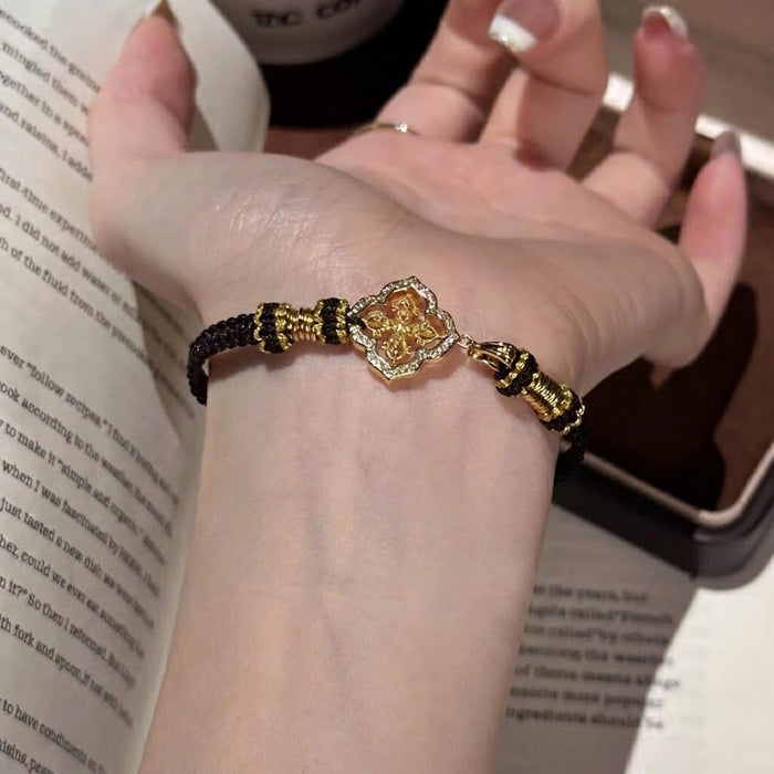 Elegant, bold, and full of refined detail, the Golden Clover Bracelet is a striking piece designed for someone who loves classic black and gold styling. Featuring a clover-inspired centerpiece with golden detailing and sparkling crystal-style accents, this bracelet brings a rich, polished look while the braided cord keeps it comfortable and easy to wear.