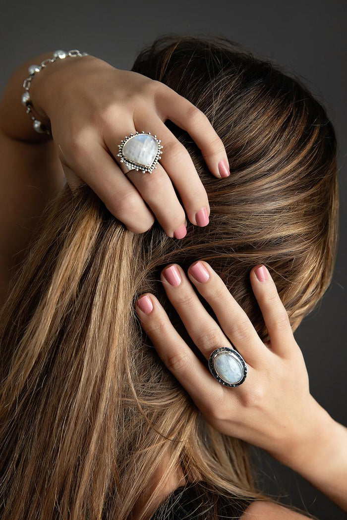 Photo of a brunette model wearing a silver oval white moonstone ring With other jewelry