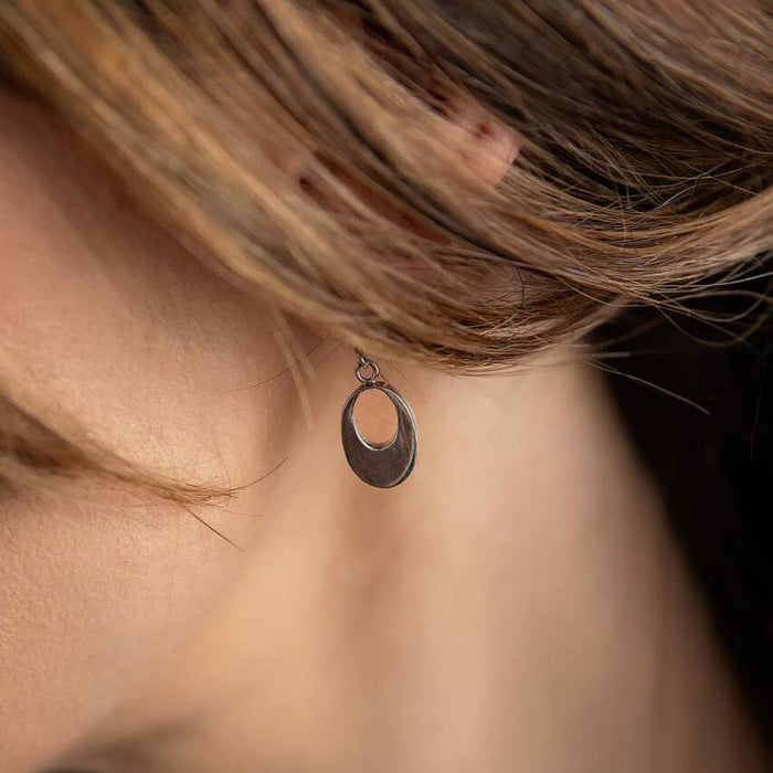 photo of a brunette model wearing a silver oval drop earring with an opening in the middle