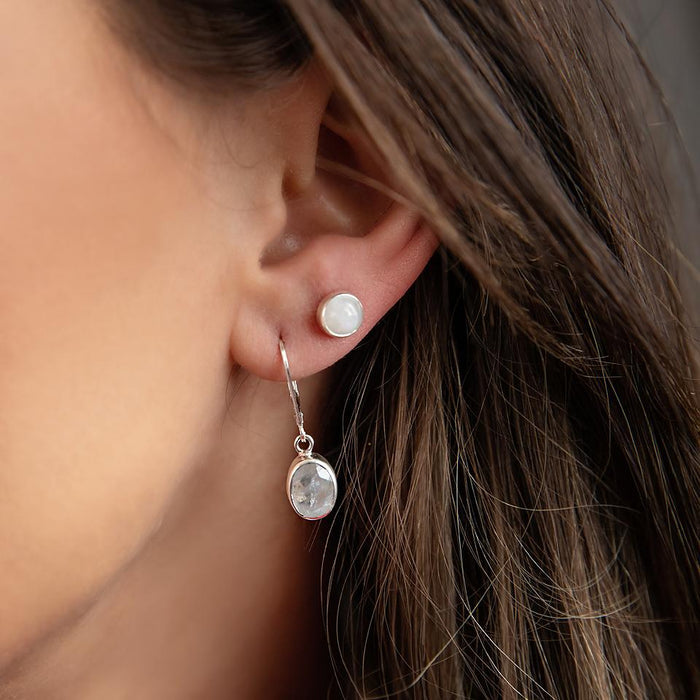 a round white moonstone stud earring on a brunette model worn as a second piercing