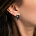 photo of a brunette model wearing a silver earring with raised bumps and black oxidation