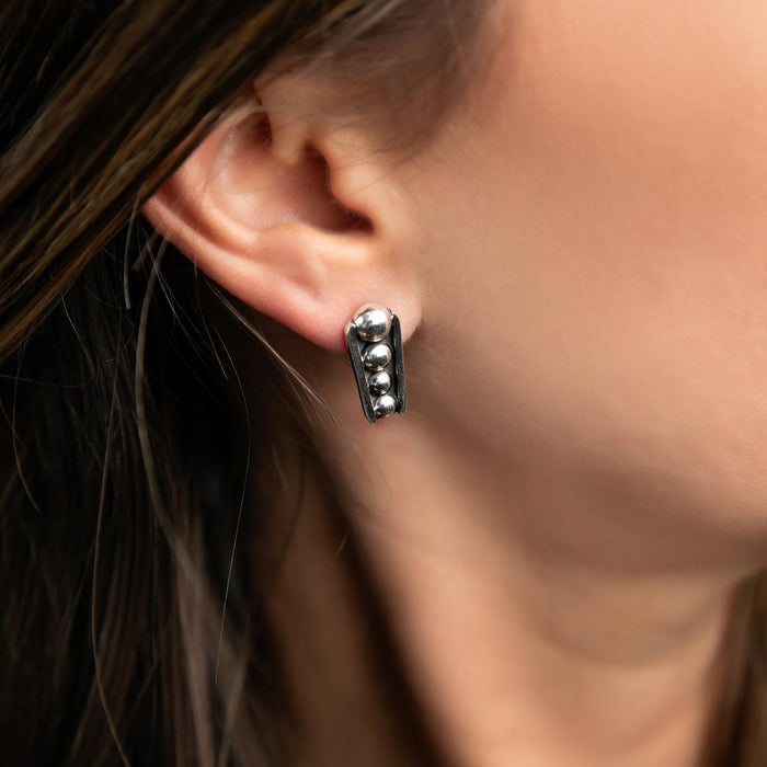 photo of a brunette model wearing a silver earring with raised bumps and black oxidation