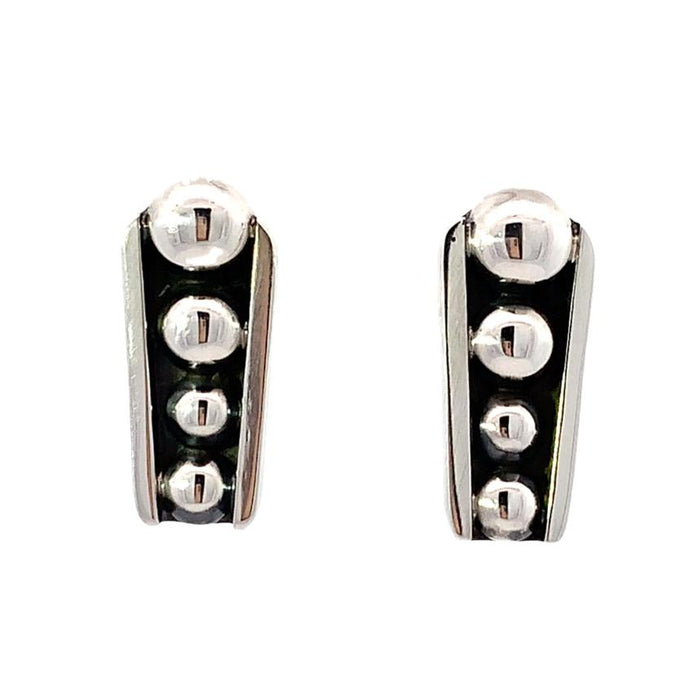 photo of silver tapering earrings with raised dots and a black oxidation on a white background, front view