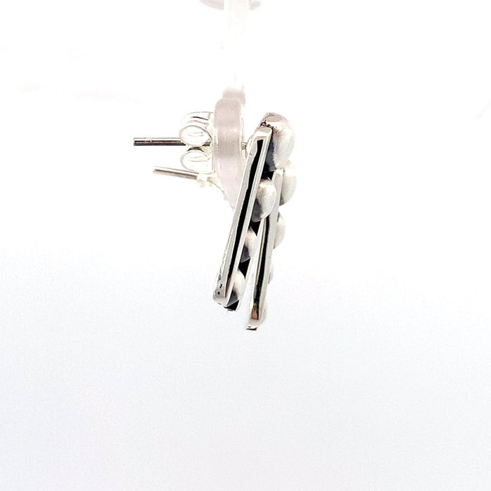 photo of silver tapering earrings with raised dots and a black oxidation on a white background, side view