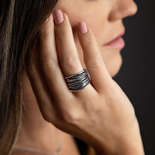 female model wearing A sterling silver wide band ring with organic texture and a dark oxidized finish