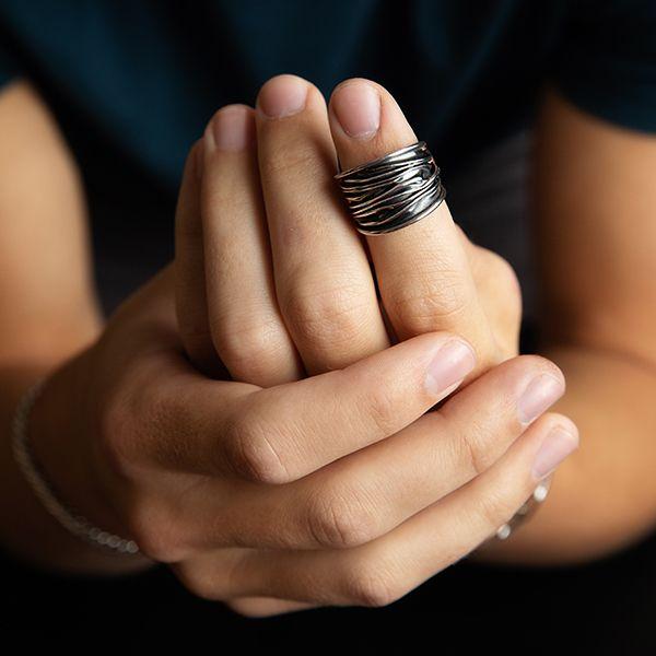 male model wearing A sterling silver wide band ring with organic texture and a dark oxidized finish