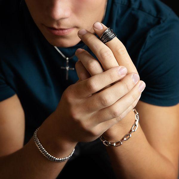 male model wearing A sterling silver wide band ring with organic texture and a dark oxidized finish