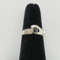 Silver ring with a blue gemstone on a black velvet stand against a light gray background