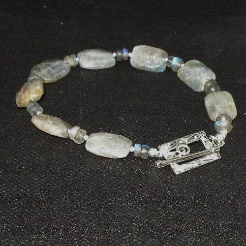 Beaded bracelet with natural stone beads and a silver clasp on a dark background