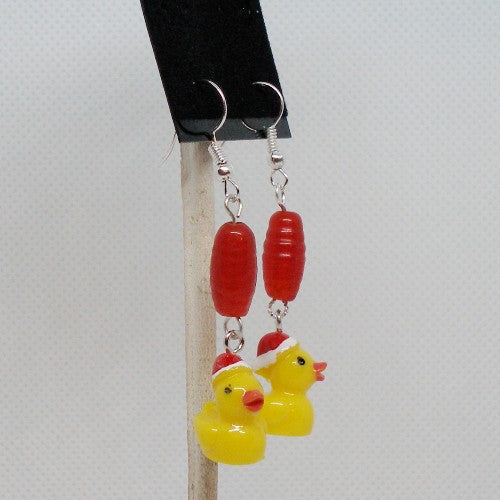 Earrings with red beads and yellow rubber duck charms on a gray background