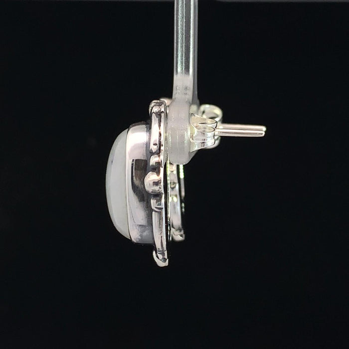 photo of a pair of silver white moonstone earrings on a black background side view