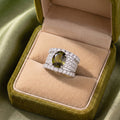 Bold, elegant, and designed with a regal statement feel, the Olive Majesty Crown Ring features a striking olive-toned oval centerpiece surrounded by layers of sparkling crystal-style accents. Its wide structured band and polished silver-tone finish give the ring a luxurious crown-inspired look that feels glamorous, sophisticated, and perfect for special occasions.