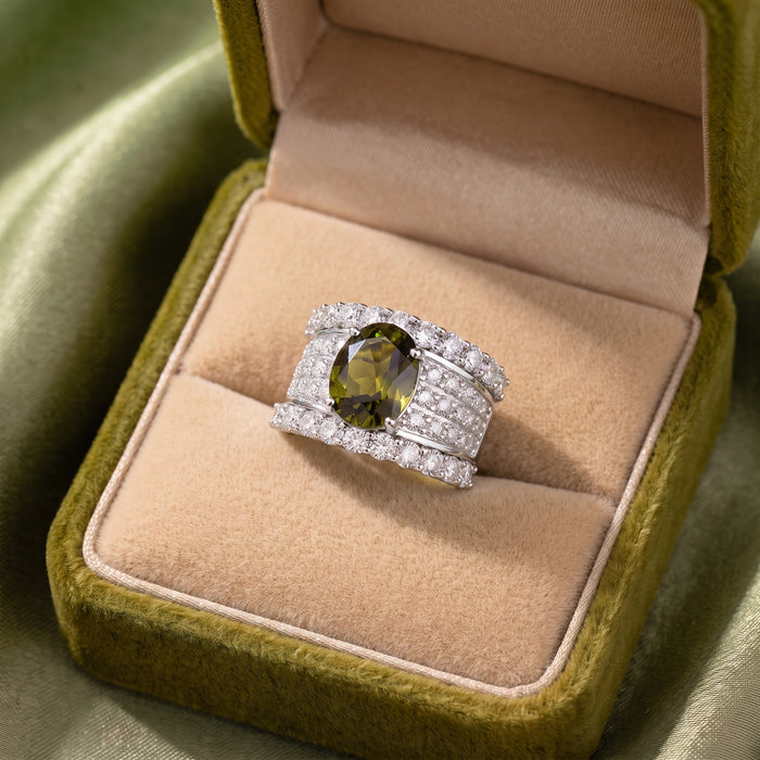 Bold, elegant, and designed with a regal statement feel, the Olive Majesty Crown Ring features a striking olive-toned oval centerpiece surrounded by layers of sparkling crystal-style accents. Its wide structured band and polished silver-tone finish give the ring a luxurious crown-inspired look that feels glamorous, sophisticated, and perfect for special occasions.