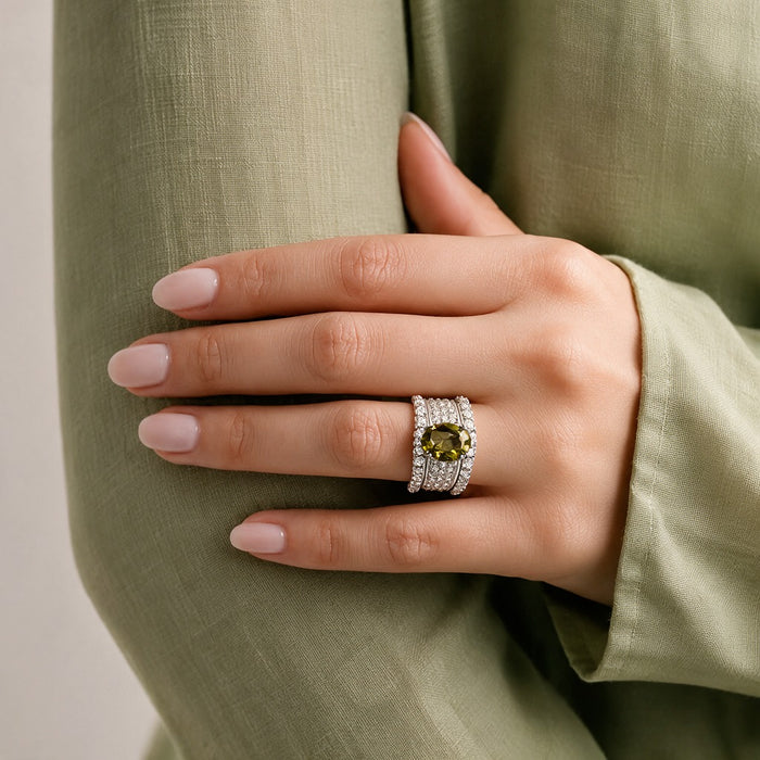 Bold, elegant, and designed with a regal statement feel, the Olive Majesty Crown Ring features a striking olive-toned oval centerpiece surrounded by layers of sparkling crystal-style accents. Its wide structured band and polished silver-tone finish give the ring a luxurious crown-inspired look that feels glamorous, sophisticated, and perfect for special occasions.
