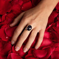 photo of a models hand wearing silver oval faceted amethyst ring on a bed of rose petals