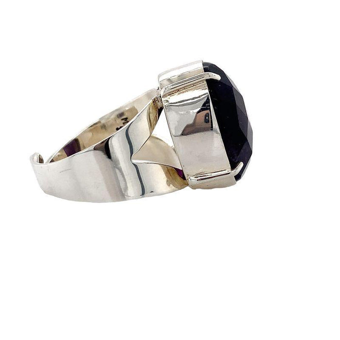 photo of a silver oval faceted amethyst ring on a white background side view