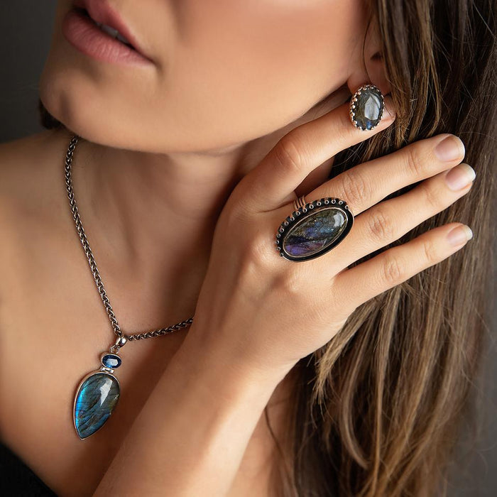 Model of a brunette model wearing an oval silver labradorite earring with other jewelry