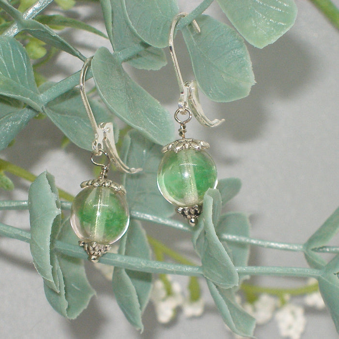 Green bead earrings hanging on green leaves