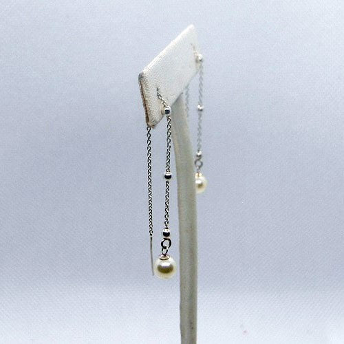 Pearl earring on a white stand against a light gray background
