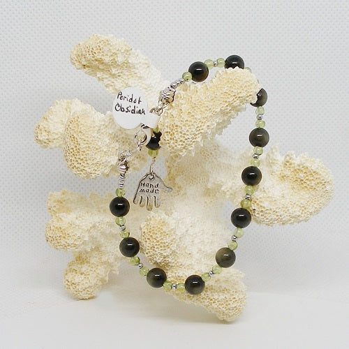 Green and Black beaded bracelet on a piece of coral against a white background