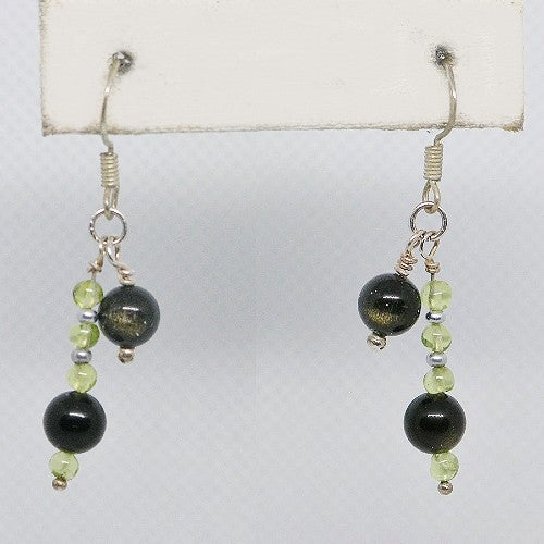 Pair of earrings with black and green beads on a white background