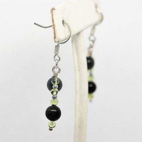Earring with black and green beads on a white background