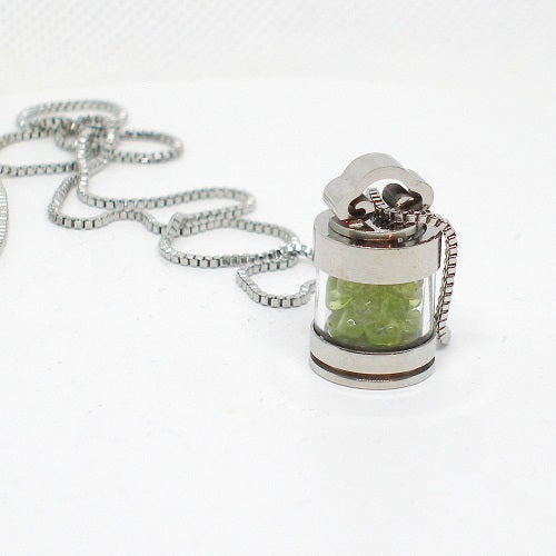 Necklace with a silver pendant containing green stones on a white background