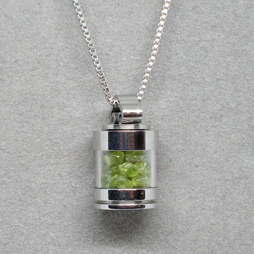 Silver pendant with green stones on a gray background