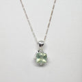Silver necklace with a green gemstone pendant on a white background
