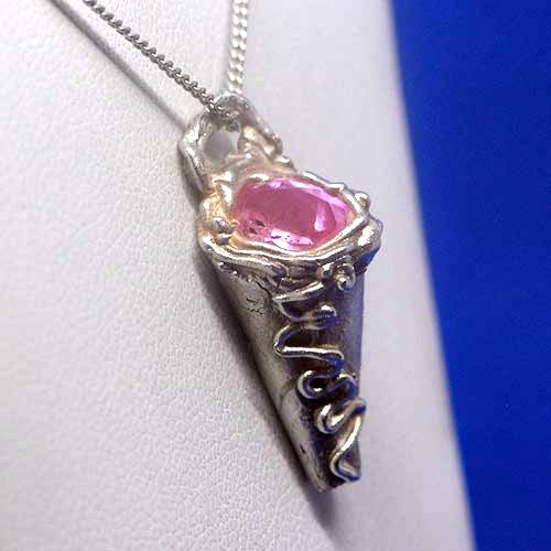 Silver pendant with a pink gemstone on a white background