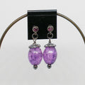 Purple beaded earrings with purple crystals on a black card against a white background
