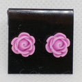 Pair of purple rose-shaped earrings on a black card with a gray background
