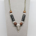 Necklace with beads and a silver raven skull pendant on a gray background