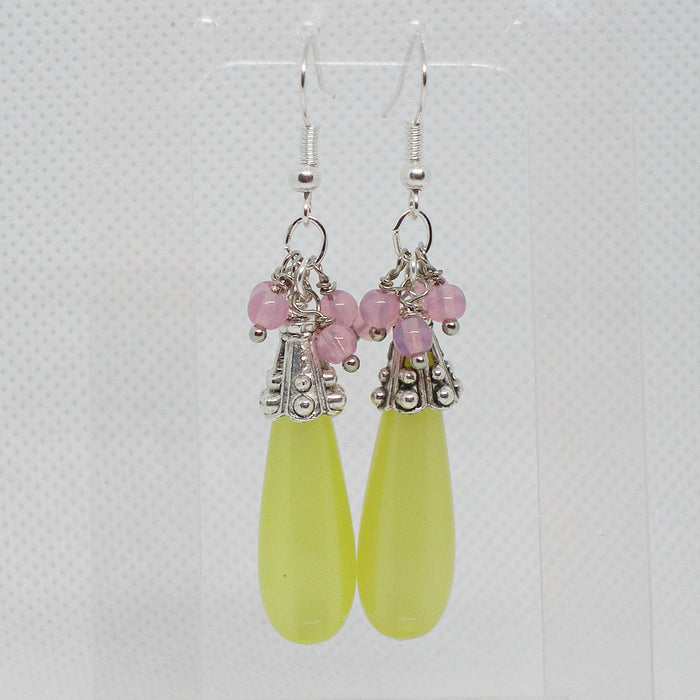 Pair of earrings with pink beads and yellow teardrop-shaped dangle on a light gray background