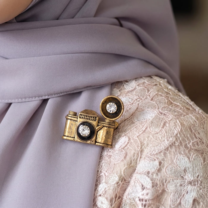 Vintage-inspired, playful, and full of character, the Retro Camera Brooch turns a classic camera silhouette into a stylish little statement piece. Featuring an antique gold-tone finish, sparkling crystal-style lens details, and a dimensional retro design, it adds a nostalgic touch to jackets, bags, scarves, and everyday outfits.