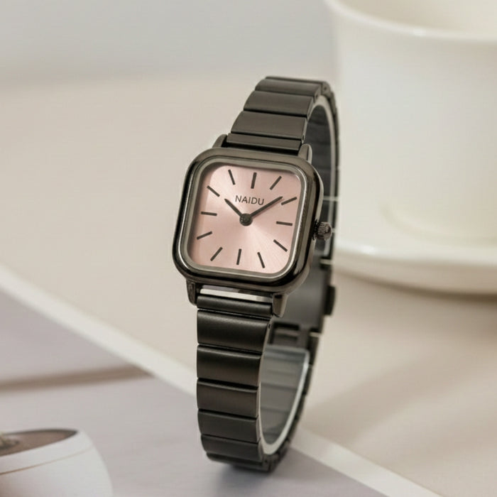 The Retro&nbsp;Noir Watch blends modern minimalism with everyday sophistication. Featuring a compact square dial with a subtle sunray texture, clean pointer markers, and a slim profile, it’s designed to sit gracefully on the wrist. Finished with a stainless-steel strap and refined detailing, this piece is made for effortless daily styling.