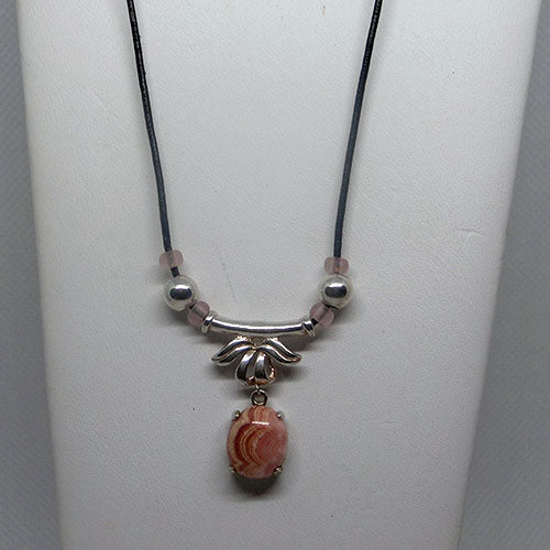 Necklace with a pink stone pendant on a white stand