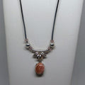 Necklace with a pink stone pendant on a white stand