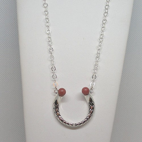 Silver necklace with a horseshoe pendant and pink stones on a white background