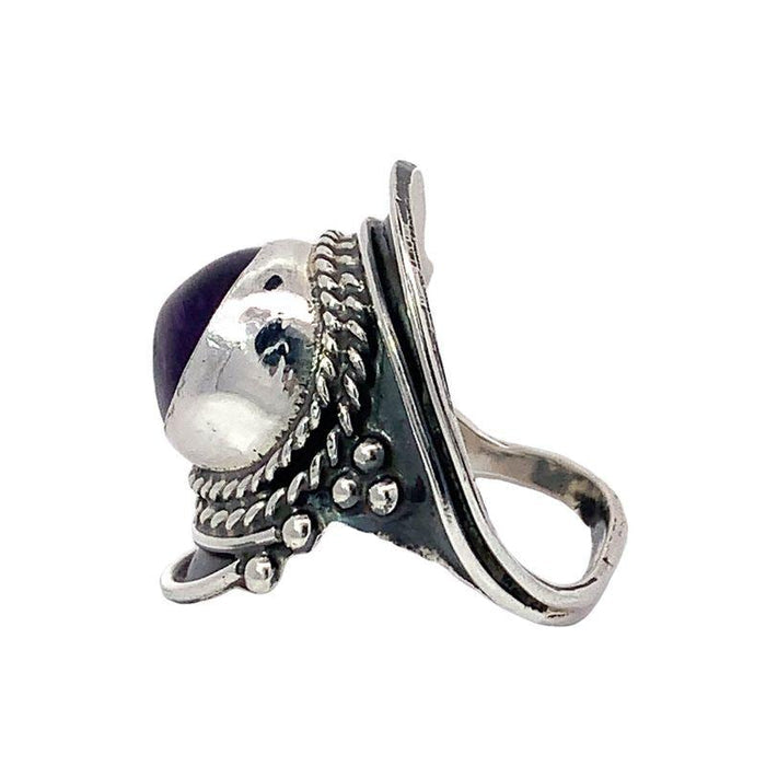 photo of a silver wide tapering band ring set with a round cabochon amethyst on a white background side view