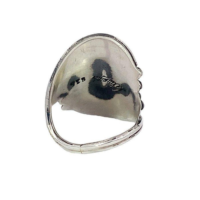 photo of a silver wide tapering band ring set with a round cabochon amethyst on a white background rear view