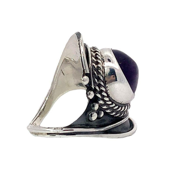 photo of a silver wide tapering band ring set with a round cabochon amethyst on a white background side view