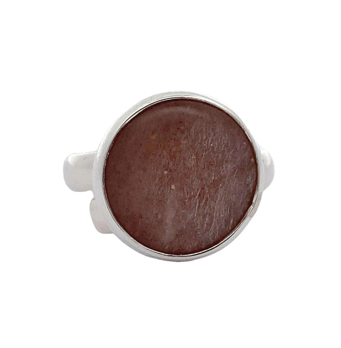 Photo of a round silver ring with a bezel set orange gem  on a white background