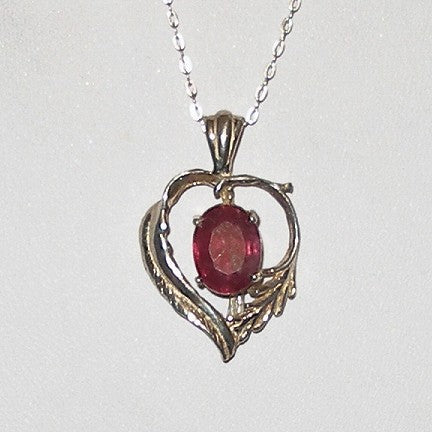 Heart-shaped pendant with a red gemstone on a white background