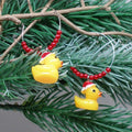 Yellow rubber duck Christmas earrings with red beads on a green branch.